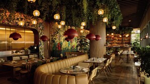 Ein Restaurant mit Sitzecken, Tischen und hängenden Pflanzen.