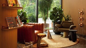 Ein modernes Wohnzimmer mit großem Fenster, einem roten Sofa, einem Couchtisch und einem Bücherregal mit Büchern.