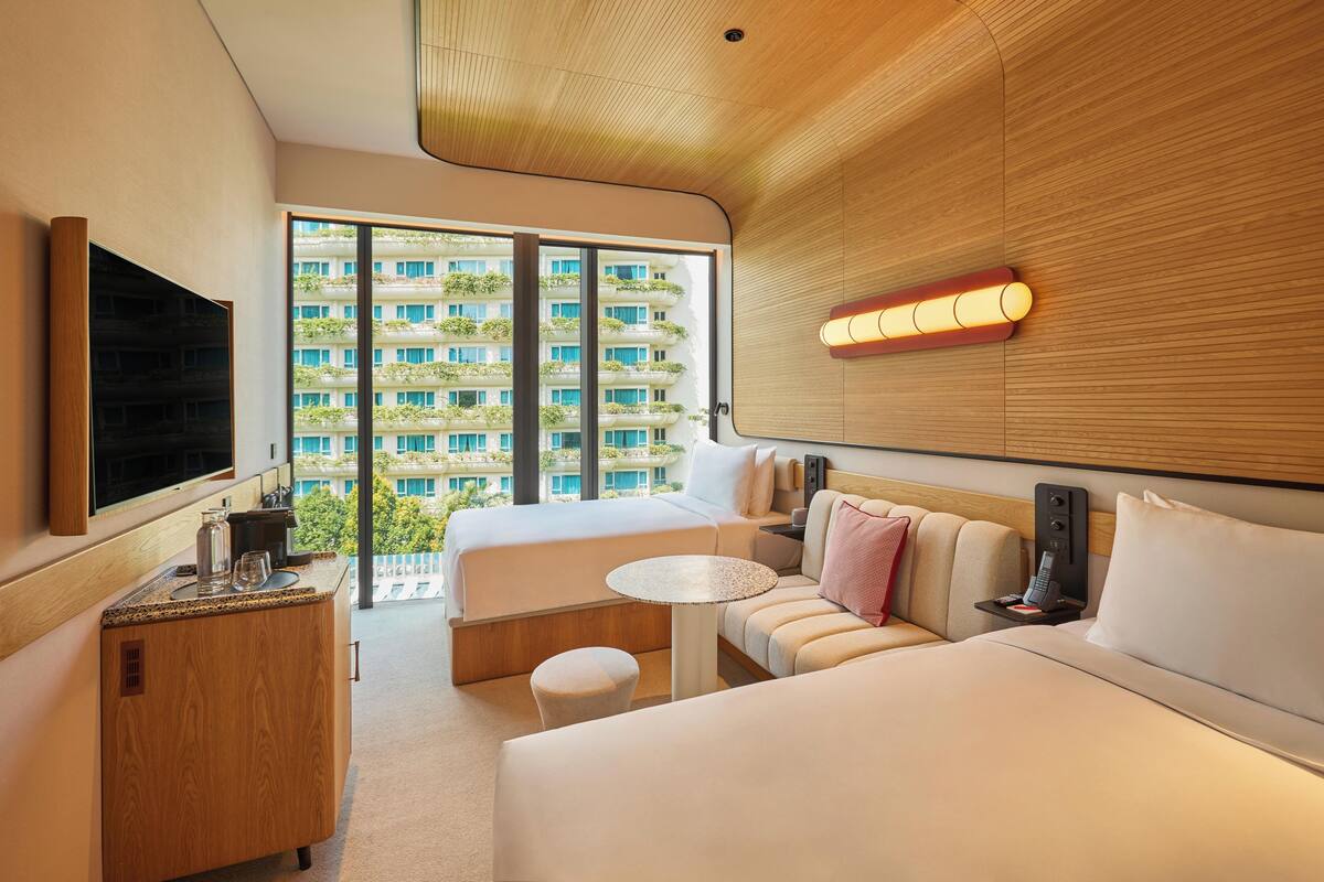 Une chambre d’hôtel moderne avec un grand lit, un canapé, une petite table et un téléviseur.