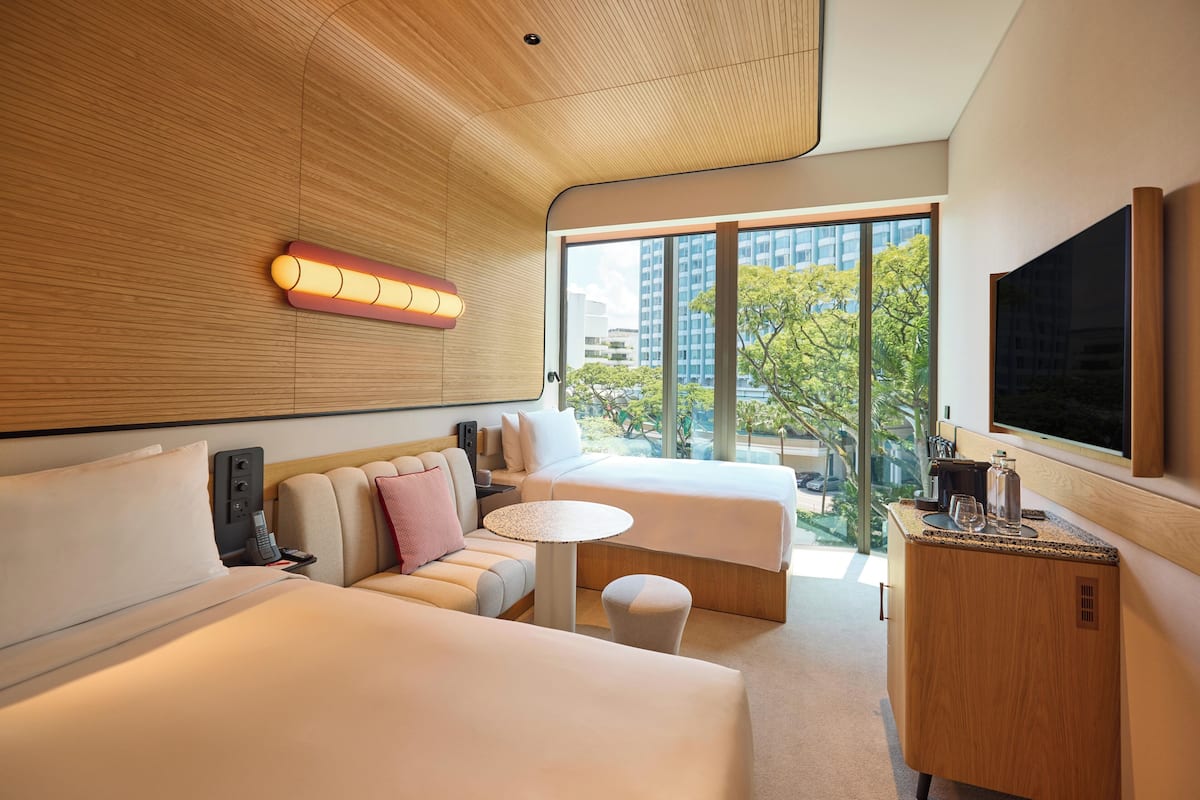 Une chambre d’hôtel moderne avec un grand lit, un canapé, une petite table et un téléviseur.