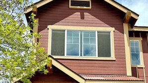 Una casa a due piani con un portico, una porta marrone e una finestra con cornice bianca.