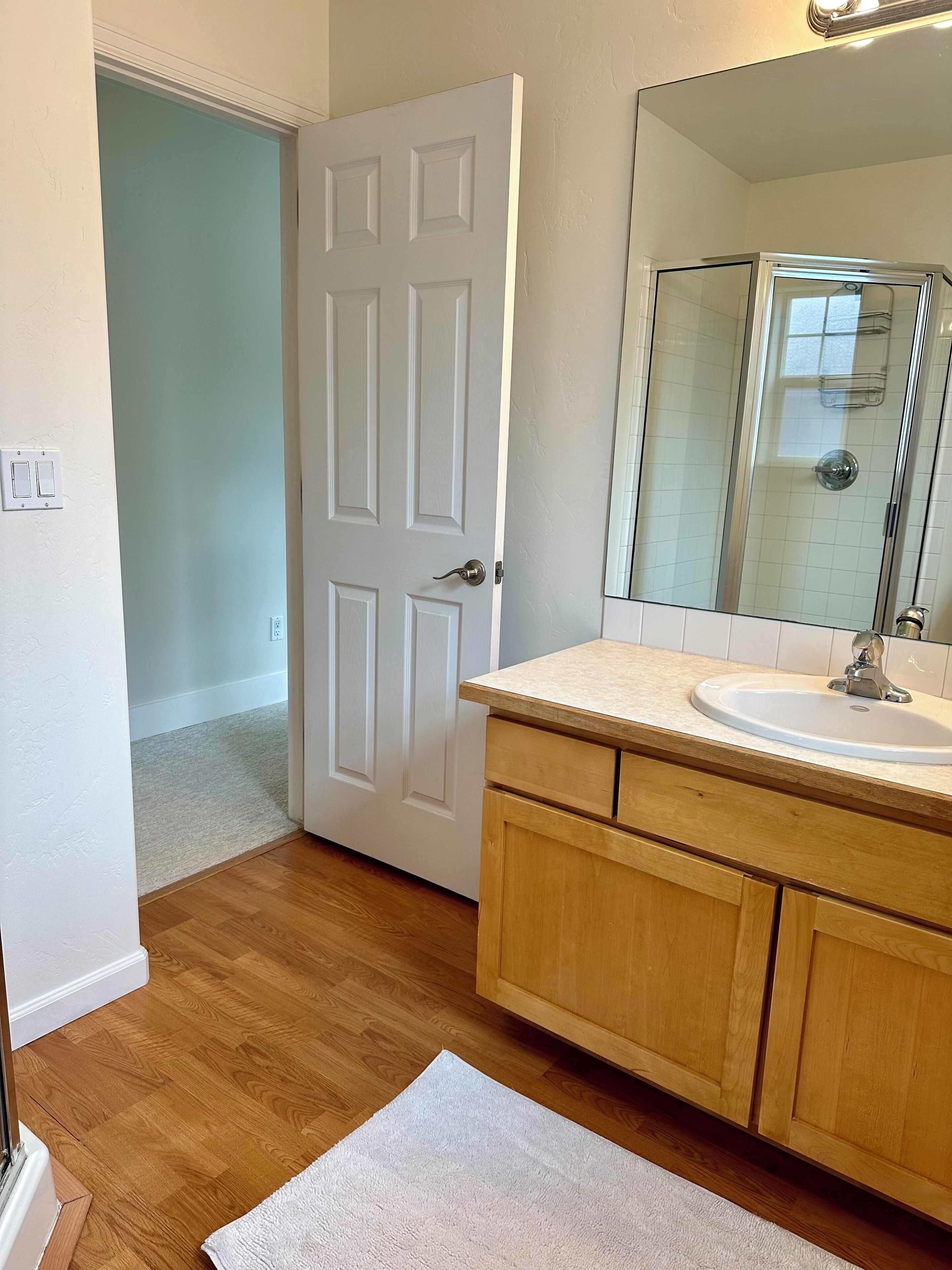 Un bagno con un mobile contenitore in legno, un lavabo bianco e uno specchio grande.