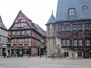 A cobblestone square with traditional half-timbered buildings, a café, and a stone building with a turret. - Martina Heydecke Comfortable Holiday Residence (Oberharz am Brocken)