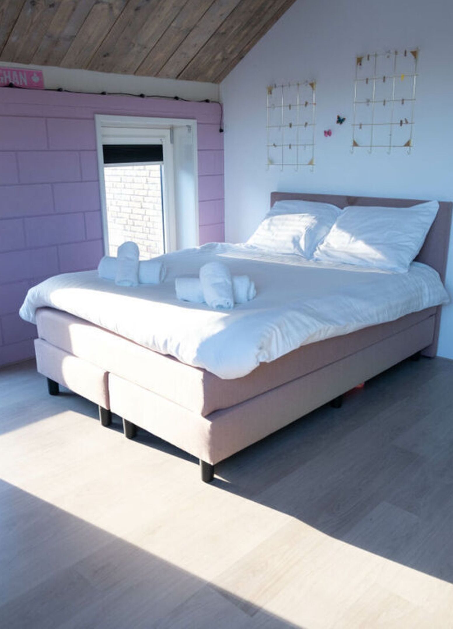 A bedroom with a bed, pillows, and a window.