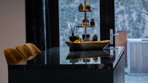 Une cuisine moderne avec un plan de travail noir, un présentoir à plantes à trois niveaux et une chaise jaune.