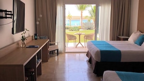 Quarto de hotel com cama, escrivaninha, cadeira, mesa pequena e vista para o exterior.