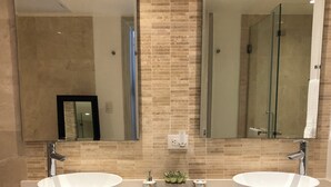 Uma casa de banho moderna com duas pias, um espelho grande e um porta-toalhas.