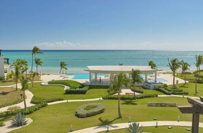 A resort with a pool, palm trees, and a view of the ocean.