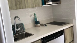Uma cozinha moderna com armários de madeira, pia de aço inoxidável, micro-ondas e lava-louças.