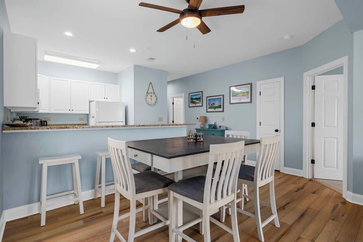 A kitchen with white cabinets, a dark countertop, and a ceiling fan.