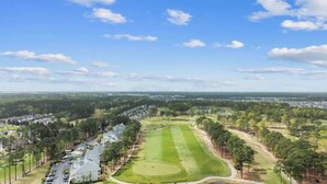 A golf course with a clear sky, surrounded by residential areas and trees. - Golf Links Residence 3BR (Myrtle Beach)