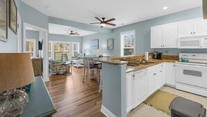 A spacious kitchen with white cabinets, a granite countertop, and a central island. - Golf Links Residence 3BR (Myrtle Beach)