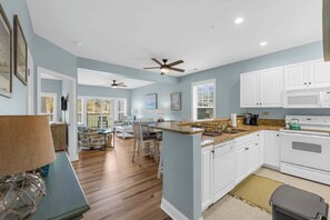 A spacious kitchen with white cabinets, a granite countertop, and a central island.