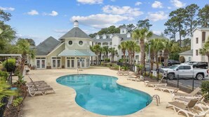 A resort with a large pool, lounge chairs, and a building with a distinctive tower. - Golf Links Residence 3BR (Myrtle Beach)