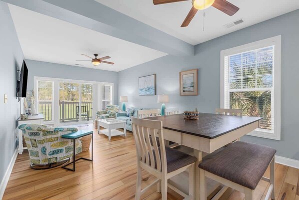 A spacious room with a dining table, chairs, a sofa, and a ceiling fan. - Golf Links Residence 3BR (Myrtle Beach)