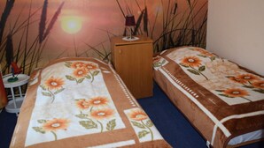Ein Schlafzimmer mit zwei Einzelbetten, einem Nachttisch und einem Wandbild mit Sonnenuntergang.