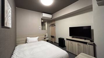 A hotel room with a bed, a TV, a desk, and a wardrobe.