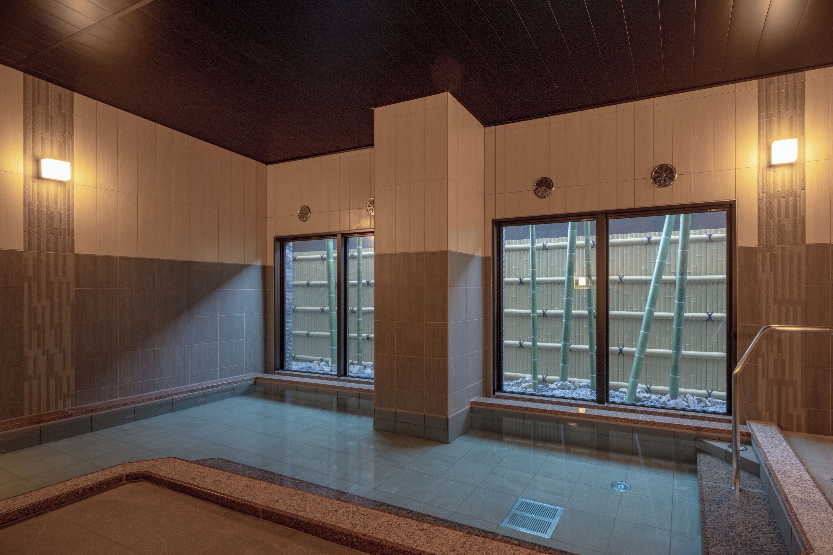A spacious indoor area with large windows, a central column, and a tiled floor.