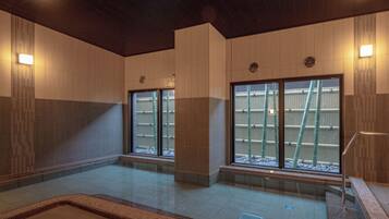 A spacious indoor area with large windows, a central column, and a tiled floor.