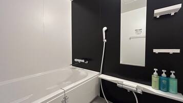 Een bad/douchecombinatie, een haardroger, handdoeken, shampoo