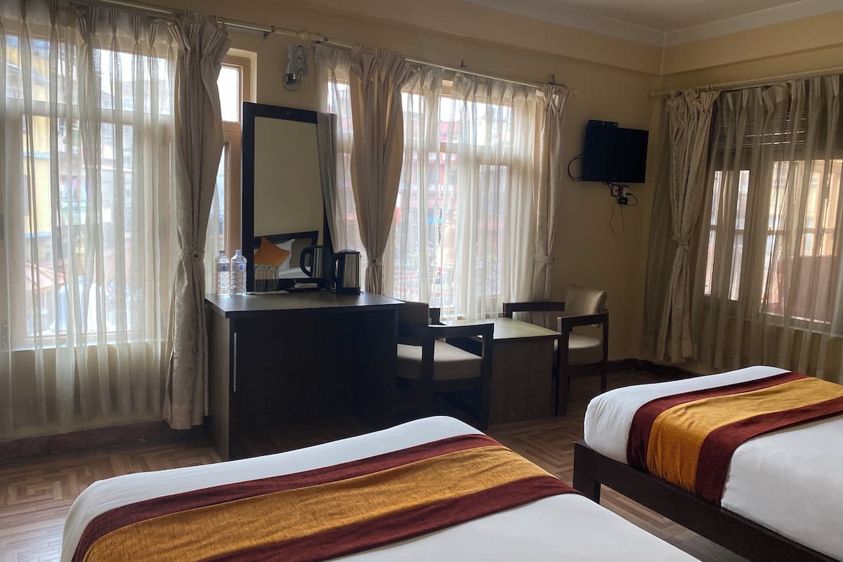 A hotel room with two beds, a desk with a chair, a television, and curtains.