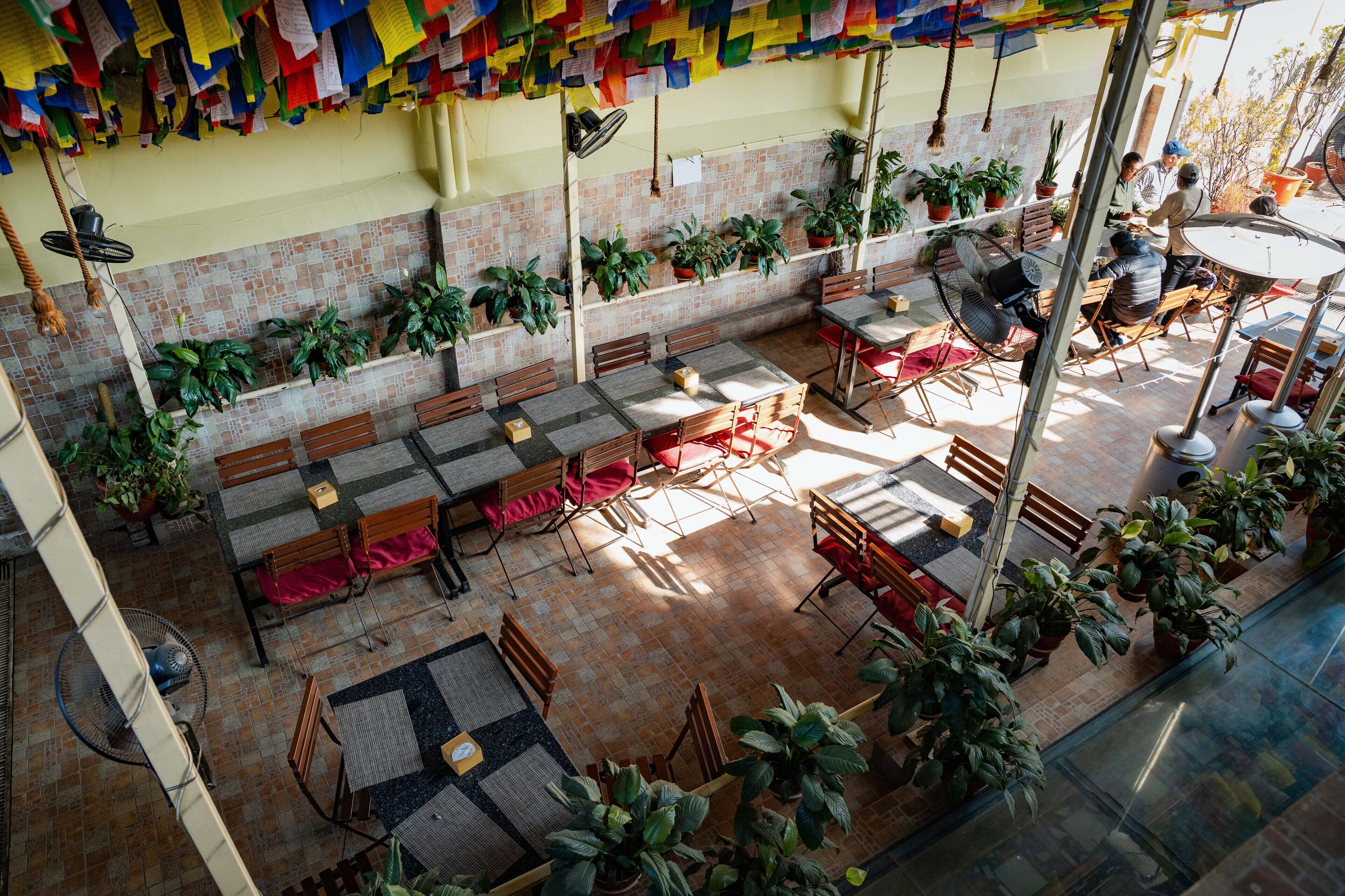 A rooftop patio with multiple seating areas, potted plants, and a view of the cityscape.