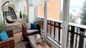 Ein Balkon mit einer Couch, einem Sessel und einem Couchtisch.