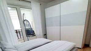 Ein Schlafzimmer mit Bett, Kleiderschrank und Blick nach draußen.