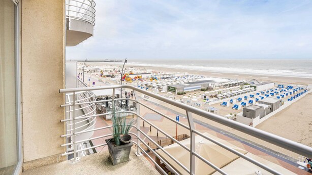 A balcony with a view of a beach and a parking area. - Beautiful Apartment With Sea-view (Blankenberge)