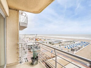 Un balcón con vista a una playa y un estacionamiento.