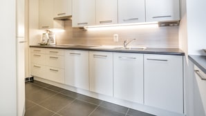 A modern kitchen with white cabinets, a stainless steel sink, and a coffee maker. - Beautiful Apartment With Sea-view (Blankenberge)
