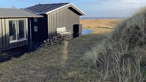 A coastal building with a bench and potted plants outside. - 4 Star Holiday Home in Hvide Sande (Hvide Sande)