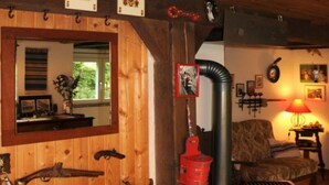 Een rustieke kamer met houten wanden, een oude kast, een openhaard en een gezellige zithoek.