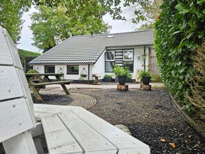A building with a tiled roof, a wooden bench, and potted plants.