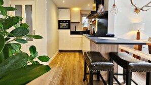 Une cuisine moderne avec un plancher en bois, un îlot central et des luminaires suspendus.