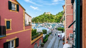 A narrow street with buildings on either side, a marina in the distance, and a hill with a castle-like structure. - Cozy Maria Apartment in Portofino, Portofino, Italy (Portofino)