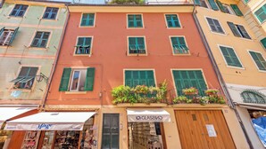 A multi-story building with green shutters, a storefront with a sign, and a wooden door. - Cozy Maria Apartment in Portofino, Portofino, Italy (Portofino)