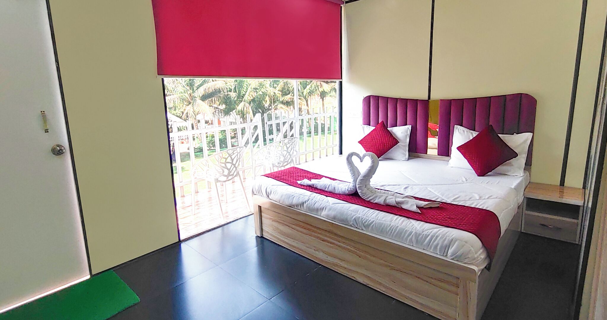 A bedroom with a bed, a balcony, and a view of palm trees.