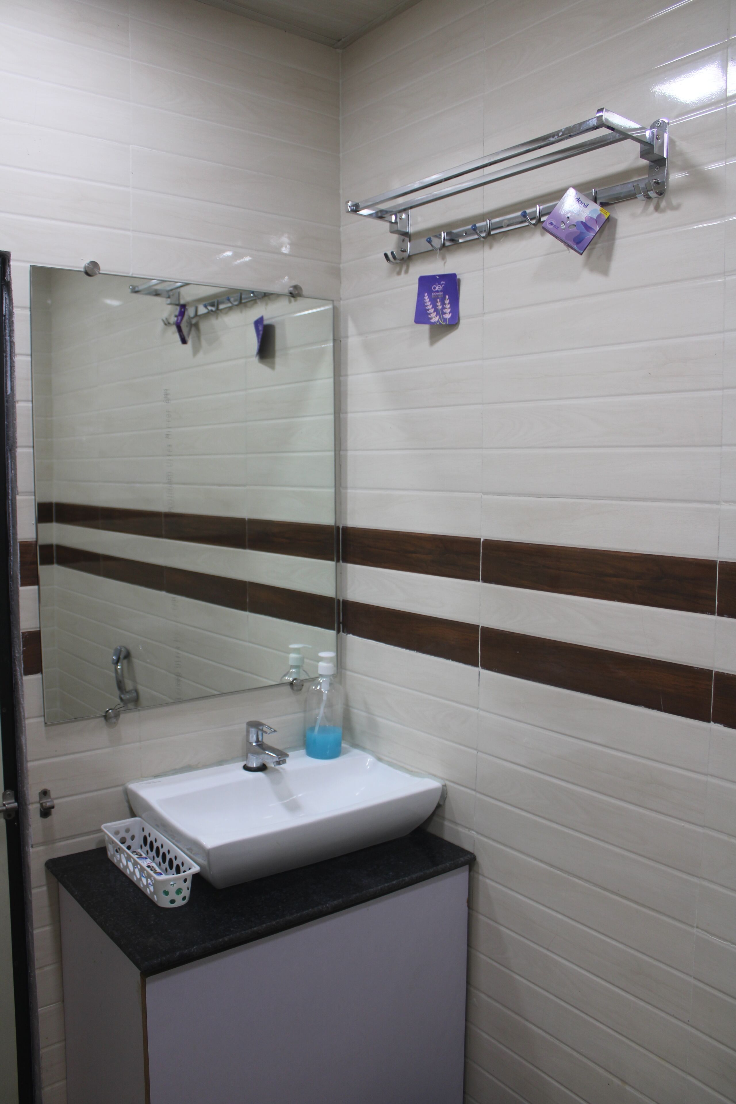 Une salle de bain avec un lavabo blanc, un miroir et un porte-serviettes.