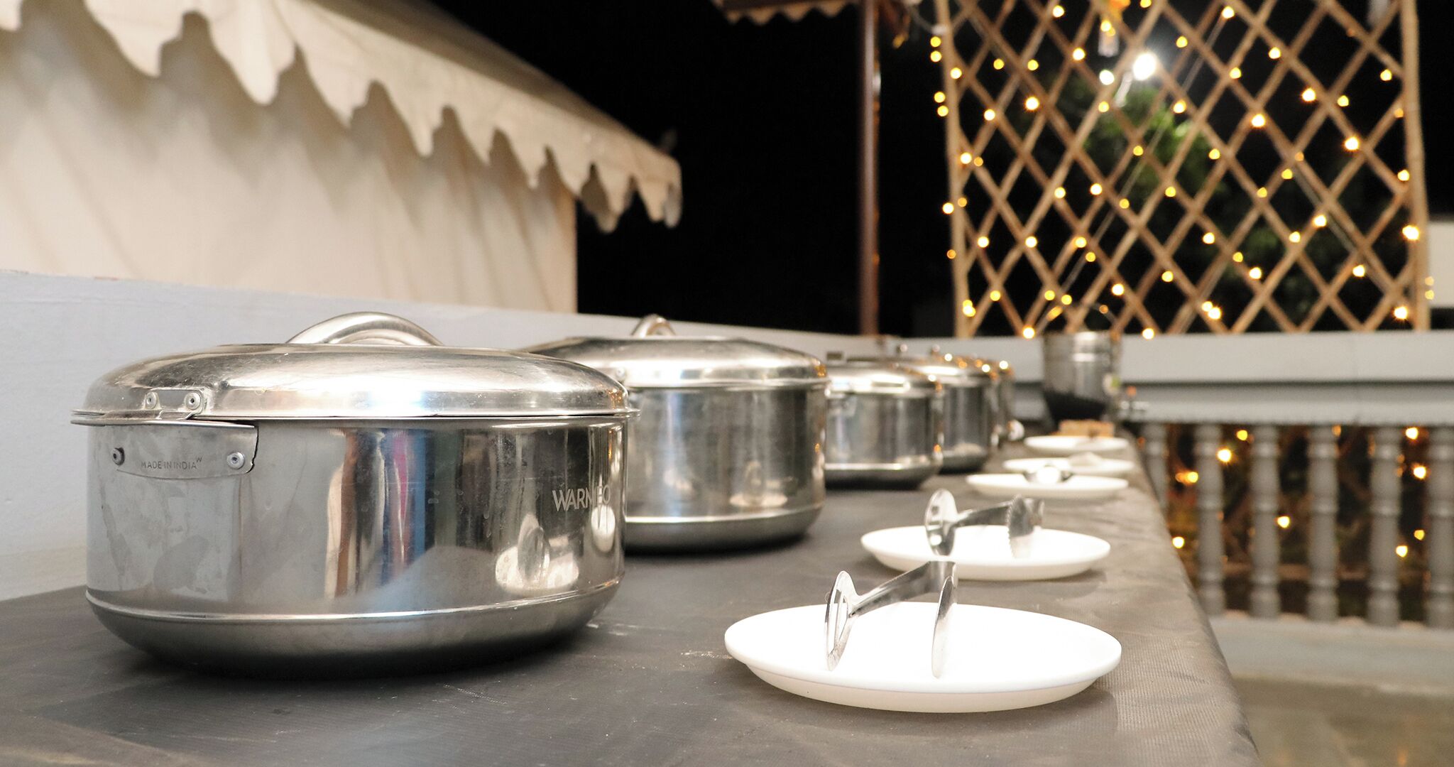 Ollas de acero inoxidable sobre una mesa, presumiblemente para un servicio de buffet o catering.