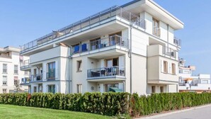 A modern multi-story residential building with balconies, a flat roof, and a well-maintained lawn. - Holiday Apartment Sanddorn WE 7 (Boergerende-Rethwisch)