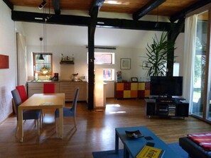 A spacious living area with a wooden dining table and chairs, a television, and a large plant. - Holiday Apartment Krote 5 (Waddeweitz)