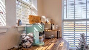 A kitchen area with a coffee machine, stacked bowls, and a Christmas tree.