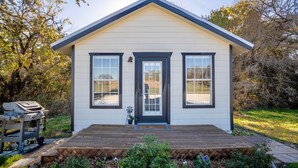 A small, single-story house with a front porch, a grill, and a well-maintained garden.