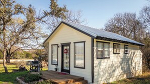 A small, single-story house with a front porch, a deck, and a garden area.