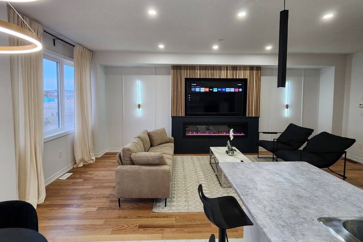 A modern living room with a sofa, a dining table, and a flat-screen TV.