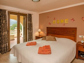A bedroom with a bed, two nightstands, a lamp, and a view of the outdoors through a sliding door. - Belvilla by OYO Casa el Paraiso (Orba)