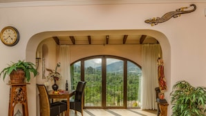 A dining area with a table, chairs, and a view through an arched window.