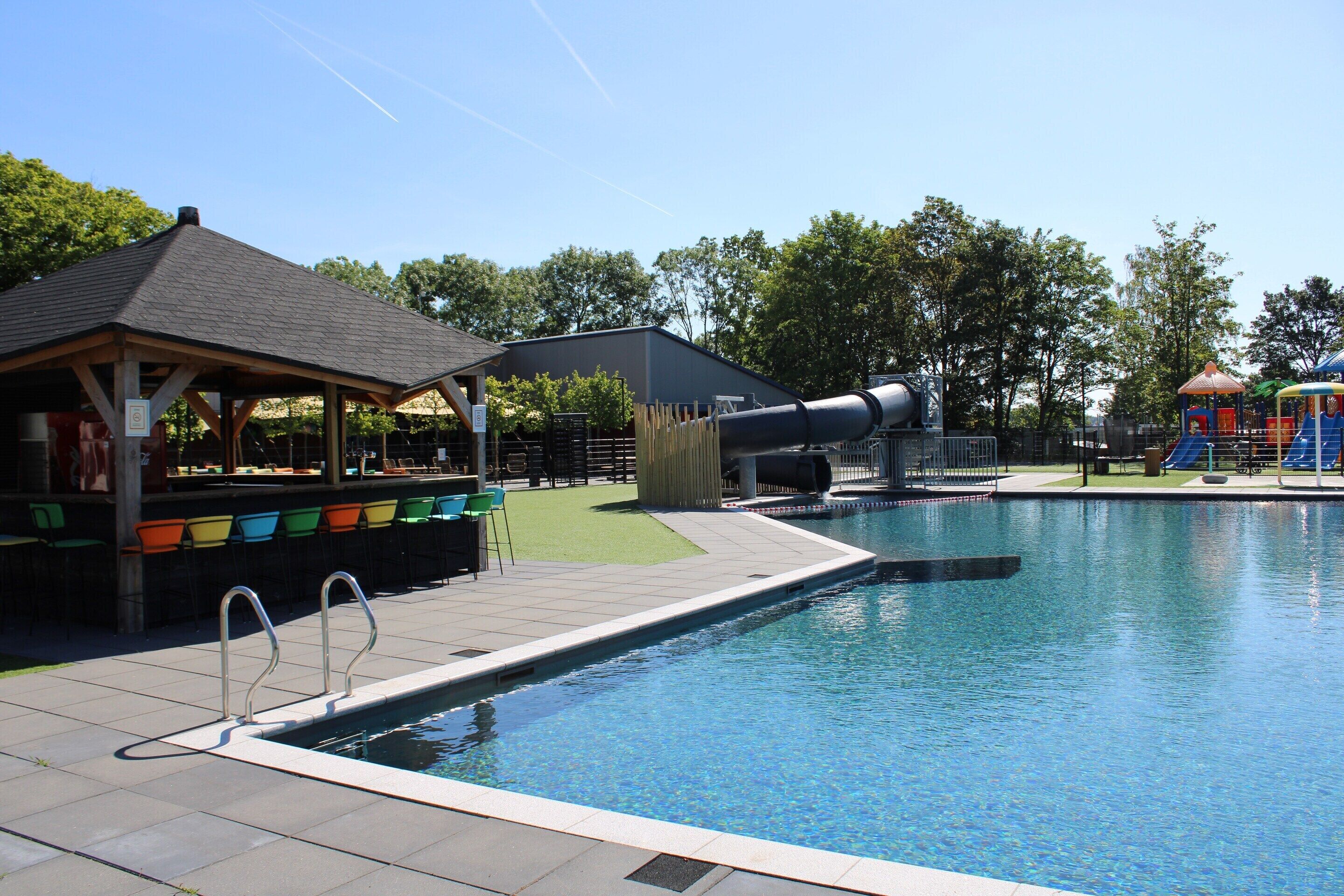 A swimming pool with a covered seating area and a slide.