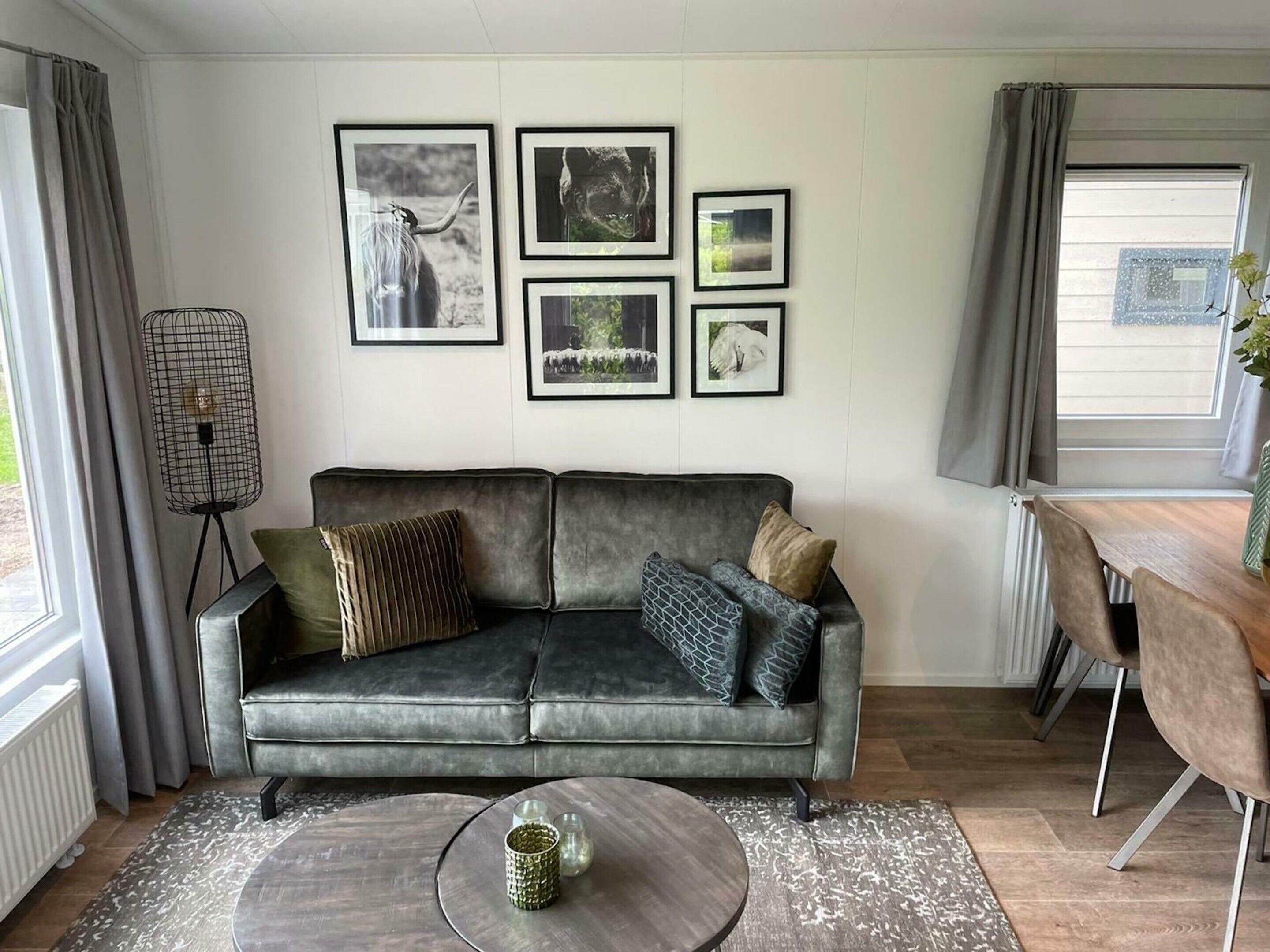 A modern living room with a grey sofa, a coffee table, and framed pictures on the wall.